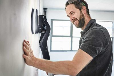 En man använder Planex med belysning för att slipa en vägg